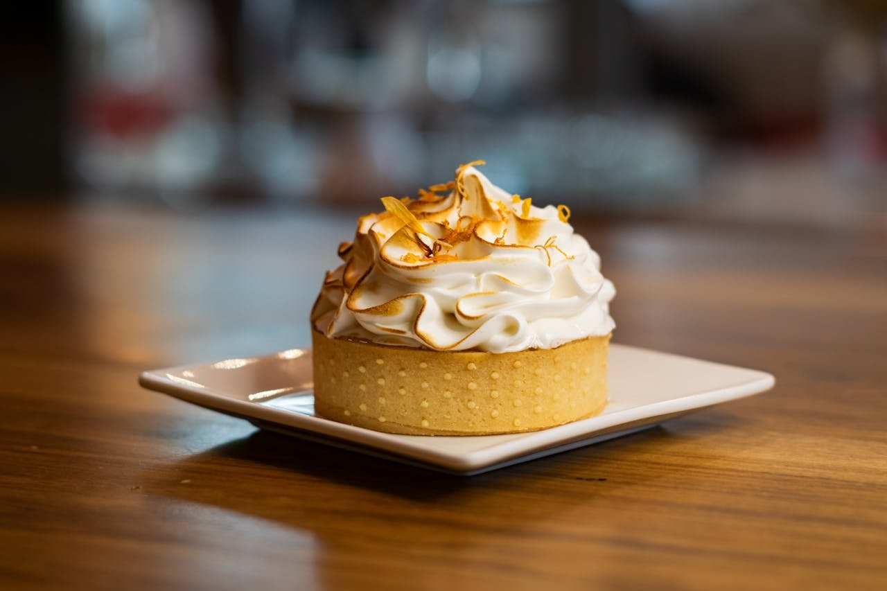 A delicious lemon meringue tart on a square plate, perfect for dessert lovers.